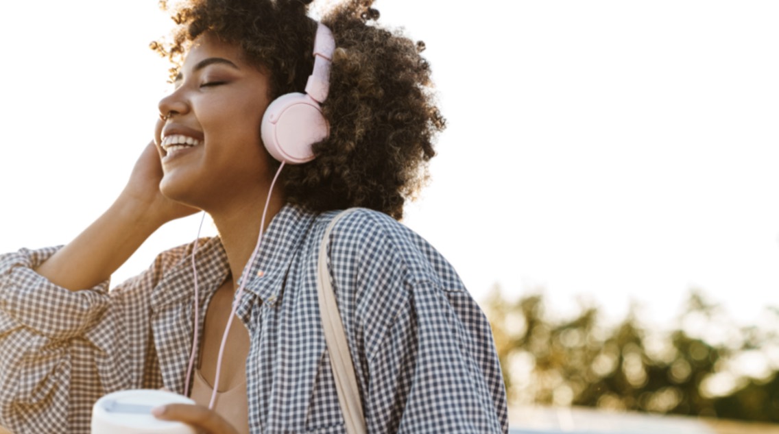 A woman listening to music through headphones outdoors.